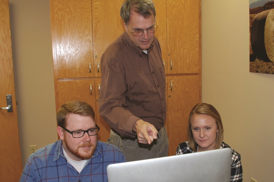 Hughes teaching two students in front of a computer