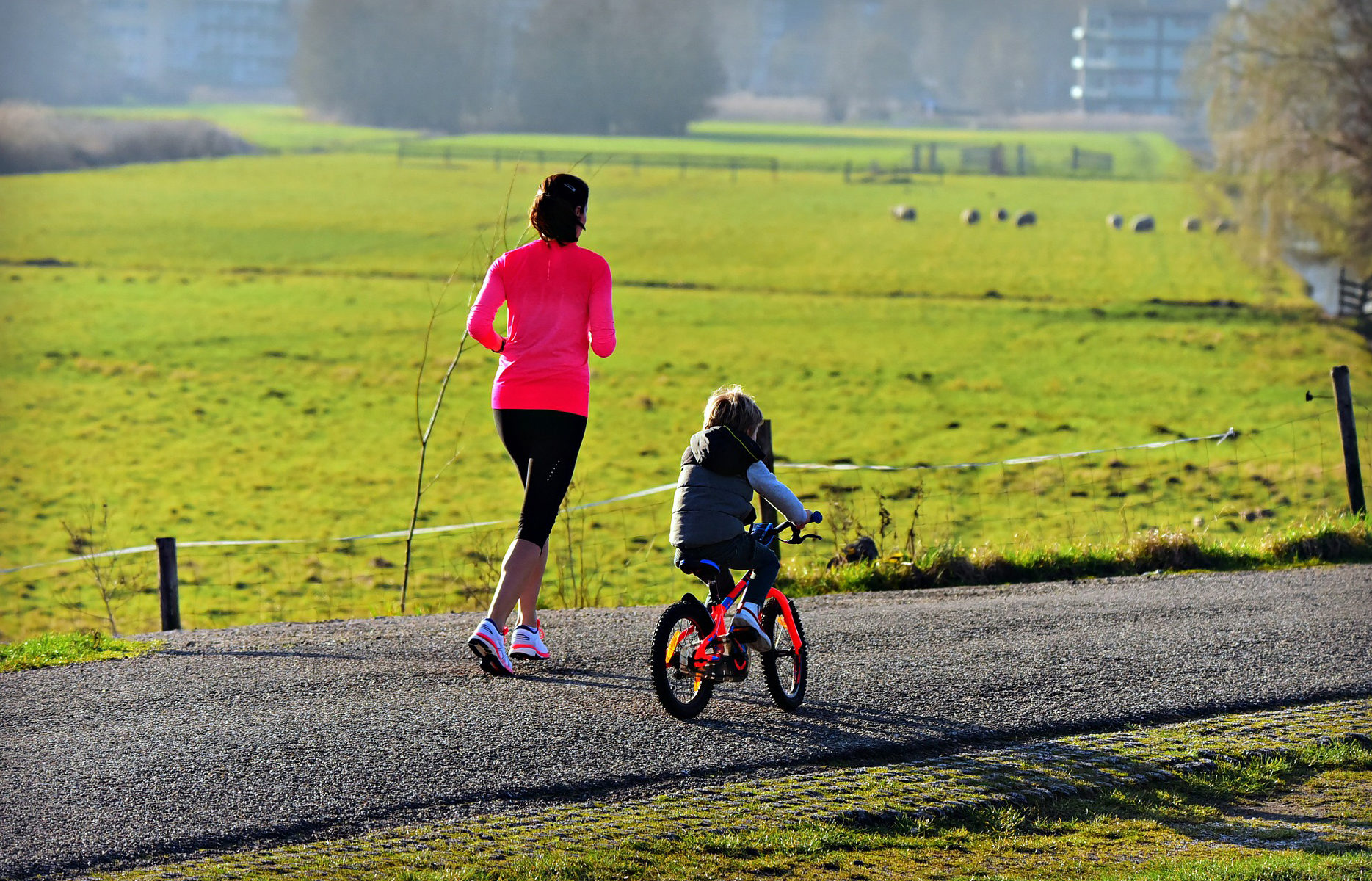 Picture of a woman running next to a child biking