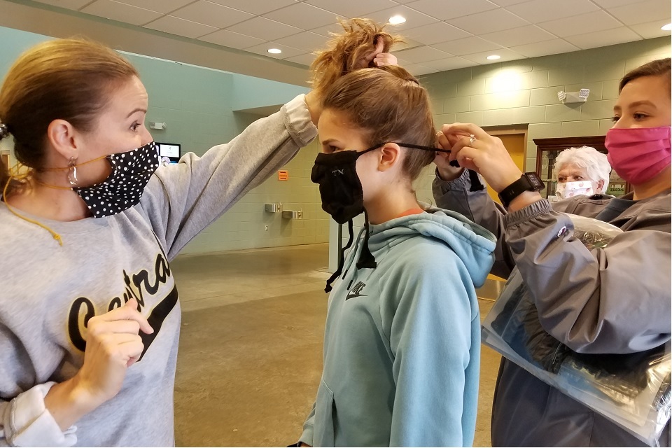 Picture of a young girl putting on a face covering