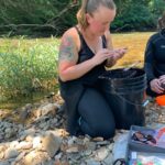 MS student Shawna Fix kneels in a stream researching the laurel dace.