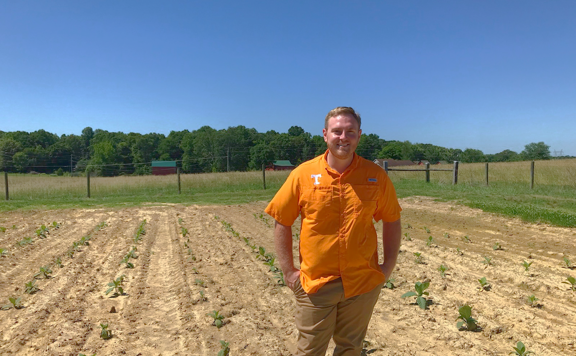 Associate professor Mitchell Richmond stands in front of a field at the Northeast Research and Education Center