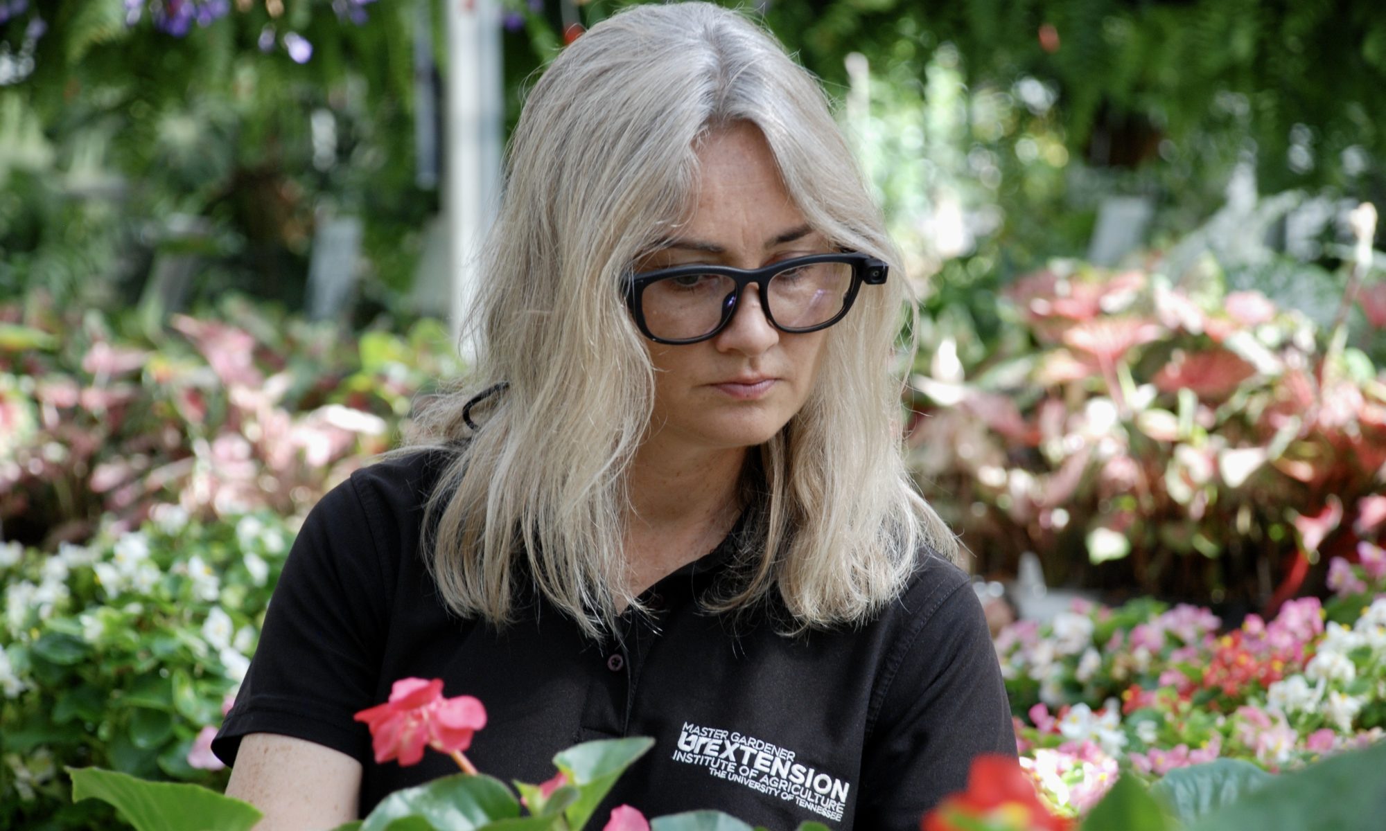 Photo of woman wearing eye-tracking glasses while looking at flowers