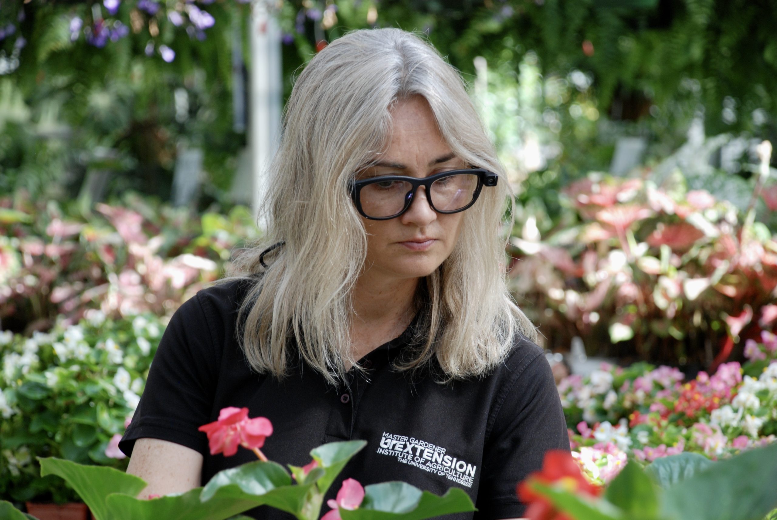 Photo of woman wearing eye-tracking glasses while looking at flowers