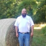 Backus standing in front of hay bale