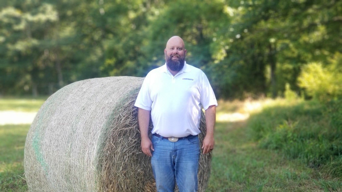 Backus standing in front of hay bale