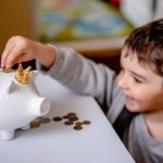 Child putting coin in piggy bank