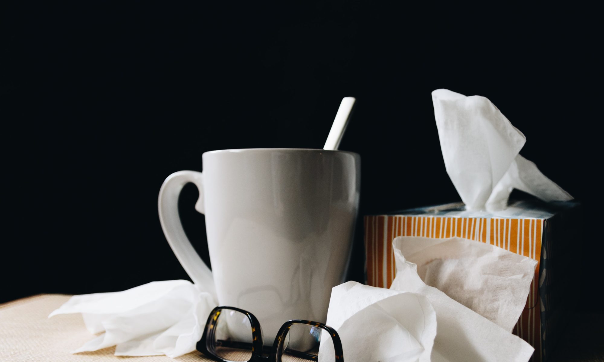 A tea mug, tissues, and glasses, on a table