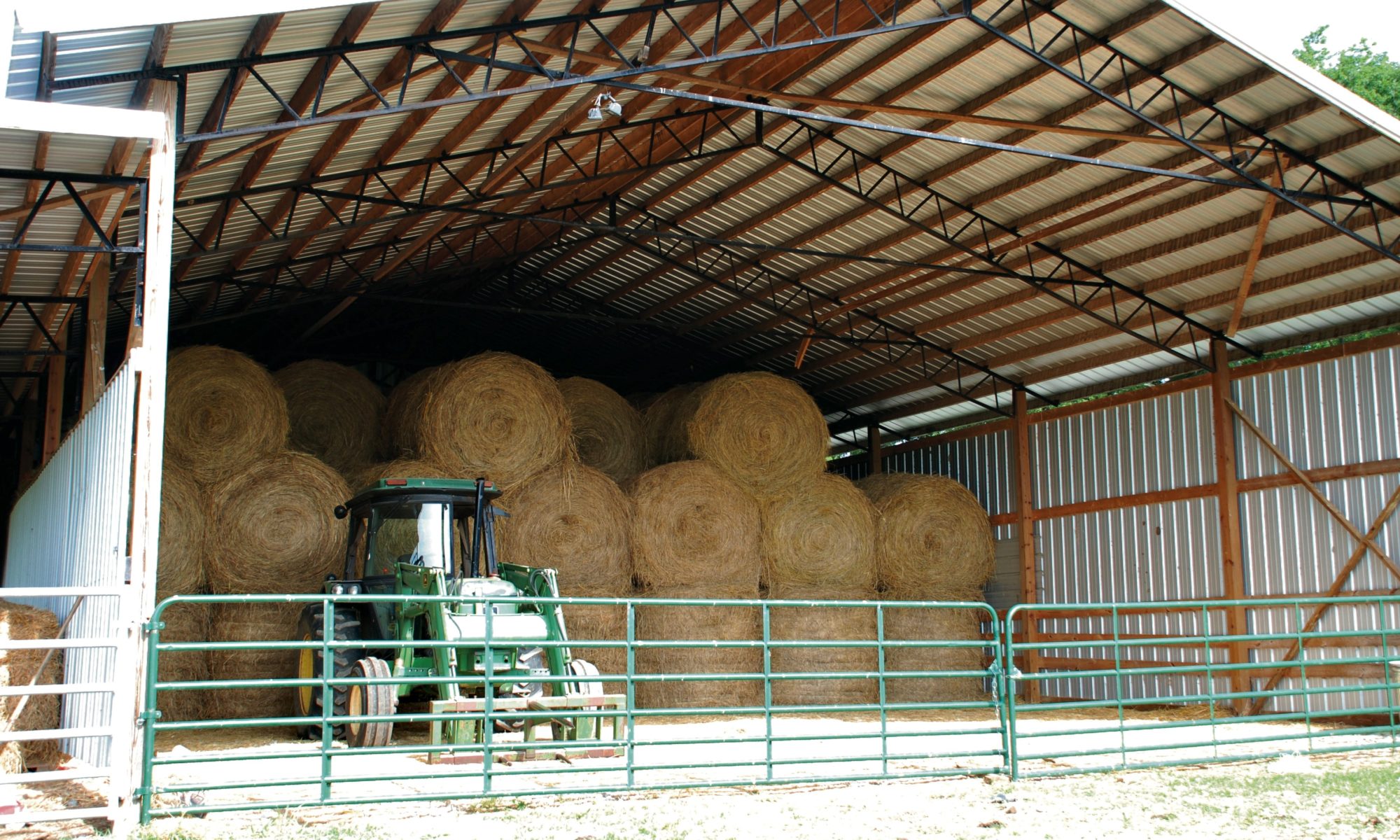 barn with bales of hay and a tractor