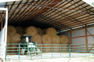 barn with bales of hay and a tractor