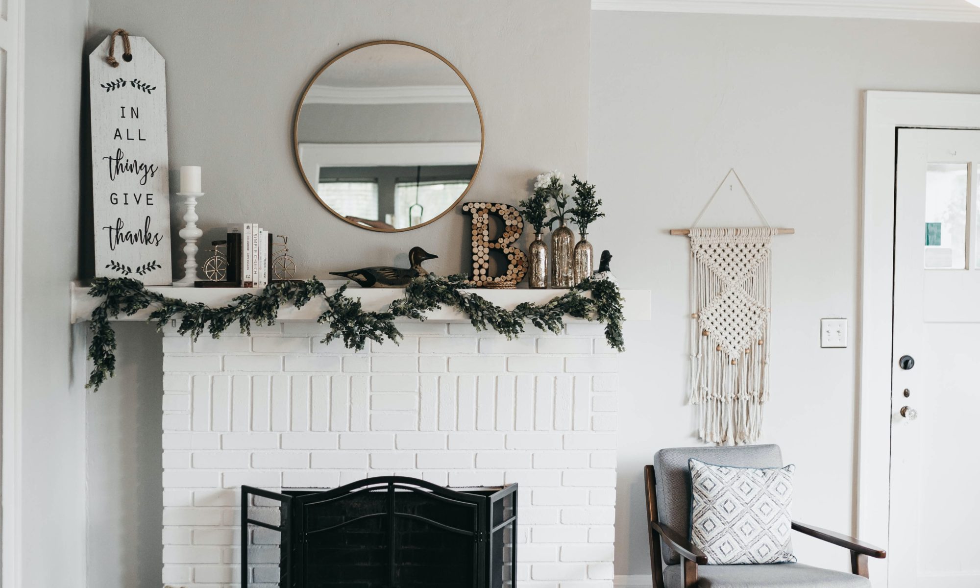 a white fireplace with holiday greenery draped across the top