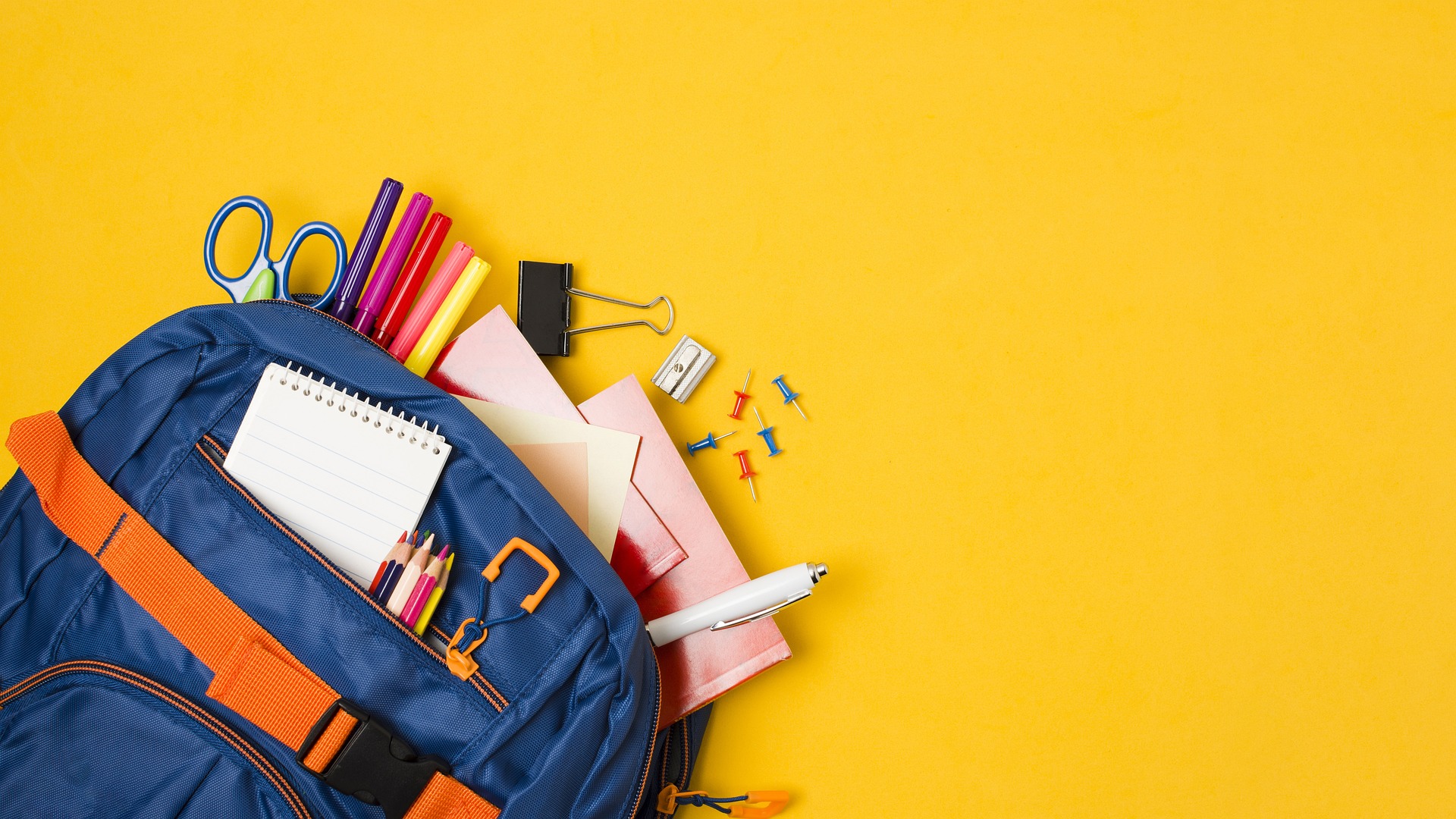 school supplies in a blue backpack with a yellow backdrop
