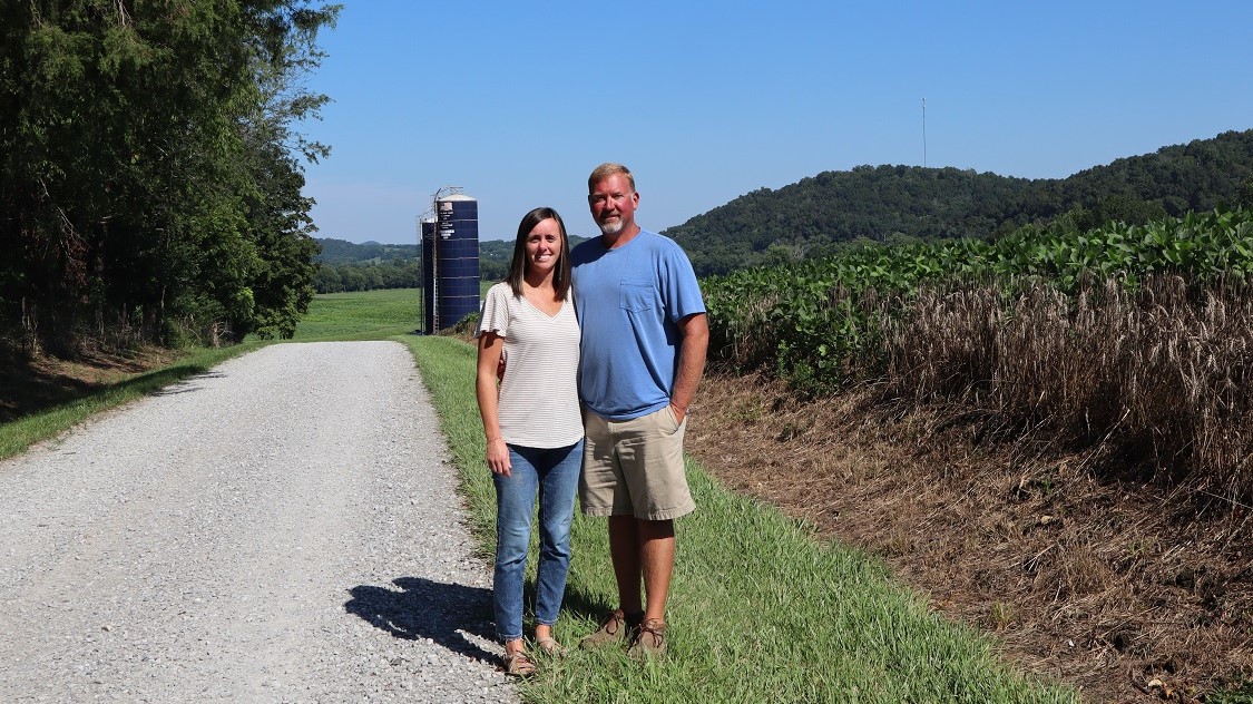 Kyle and Miranda Owen stand in a gravel lane on their farm