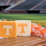 All vol cheese blocks on a table with orange and white streamers surrounding it. Neyland stadium bleachers are in the background