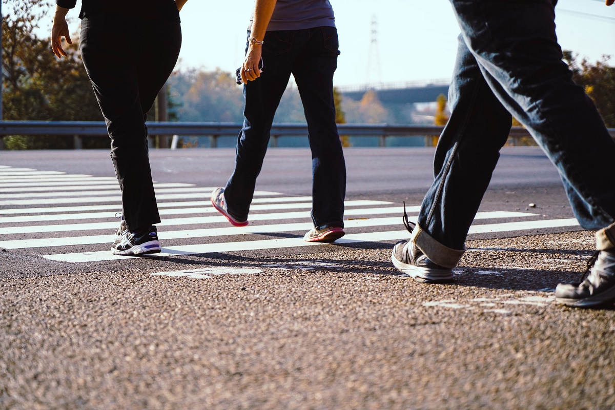 close up of three people's legs as they walk across a crosswalk.