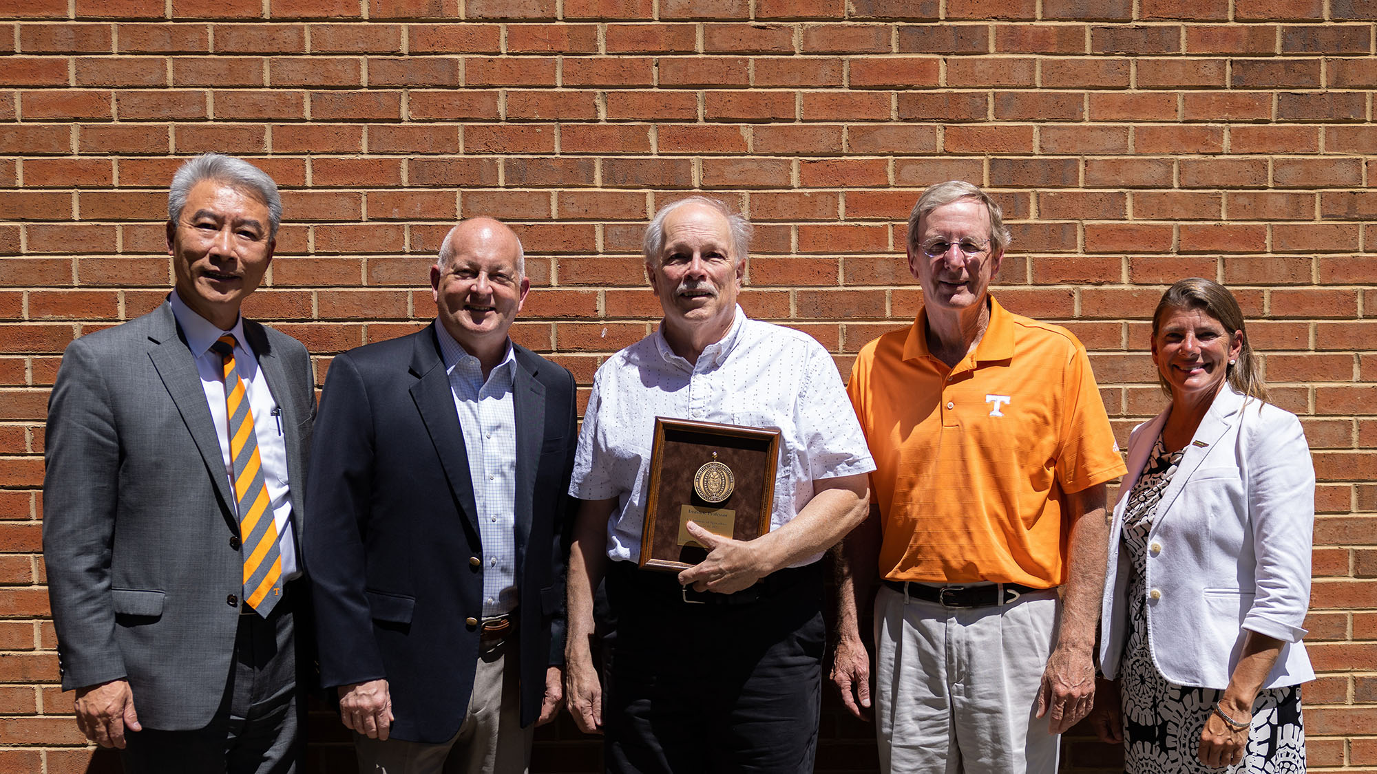 Left to right: Dean Xin, Dr. Carver, Ernest Bernard, Dr. Thompson, Dean Stokes pose in front of a brick wall. Ernest holds his award