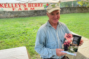 producer at farmers market holding a copy of UT Extension publication, PB 1918 and smiling at camera