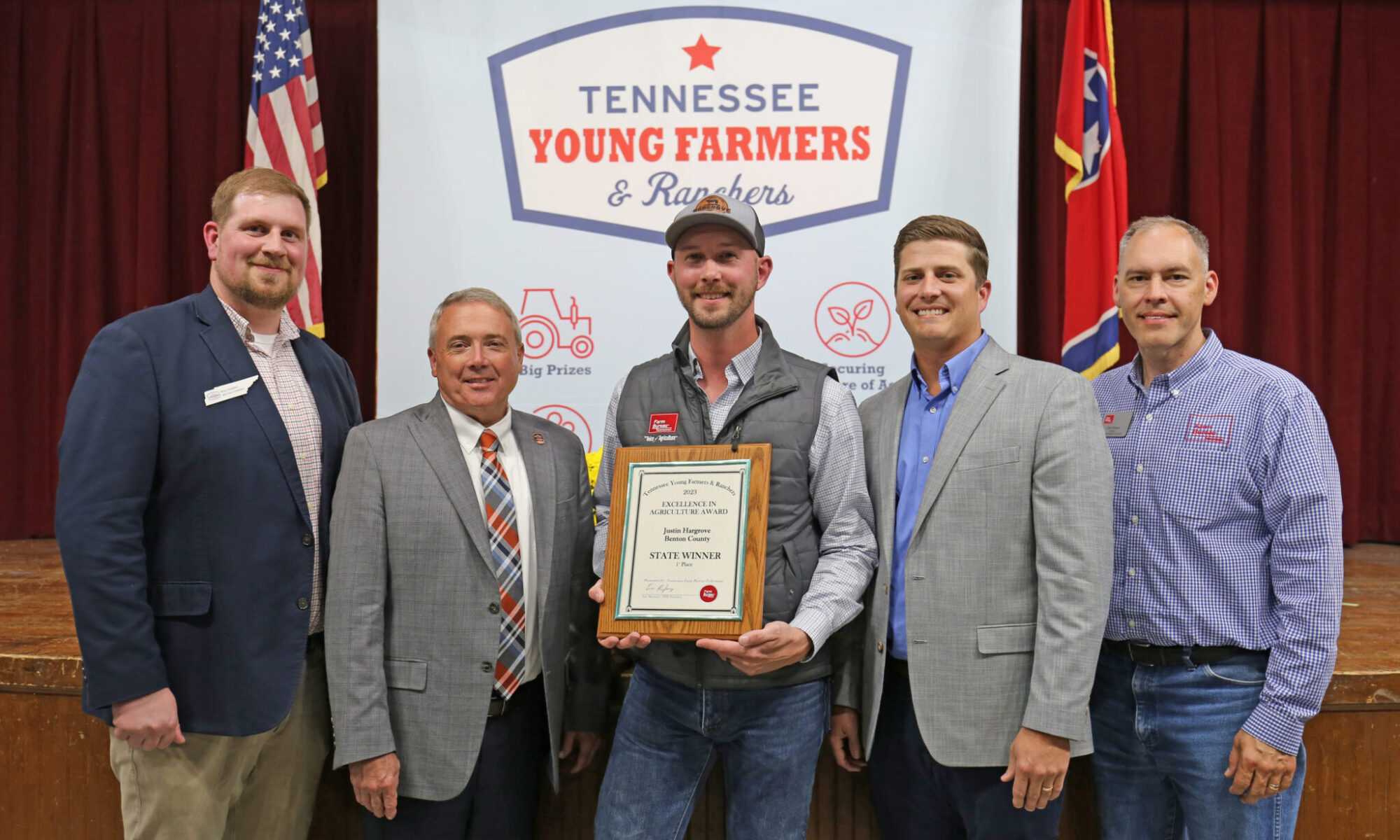 Justin Hargrove holds his award with two people on either side of him.