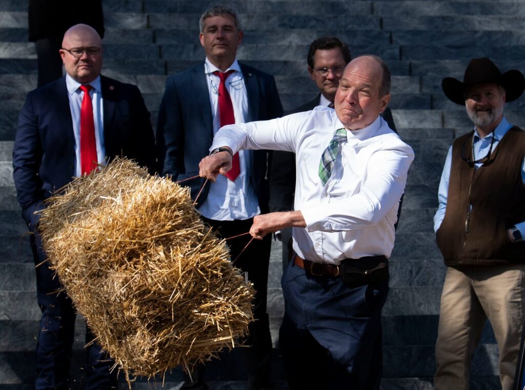 A man throws a bale of straw during a competition at Ag Day on the Hill