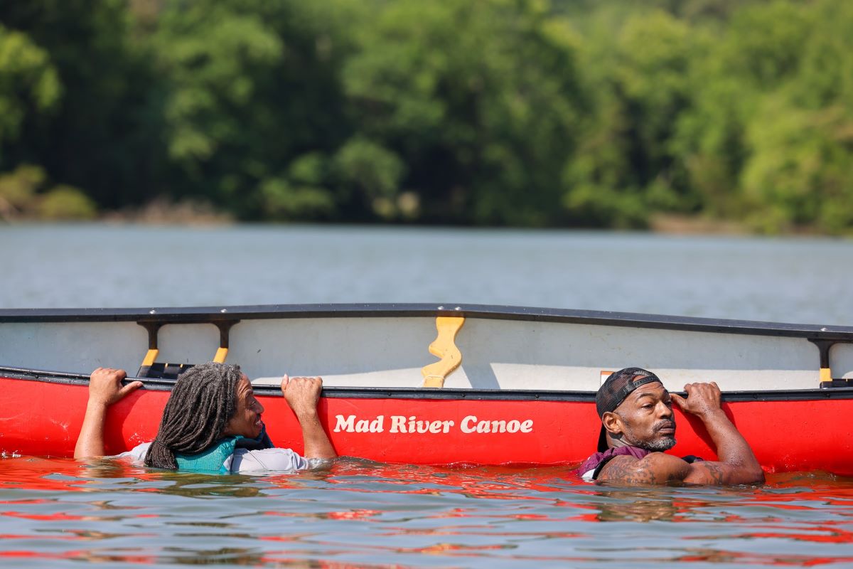 Two men hanging onto the side of a canoe in water