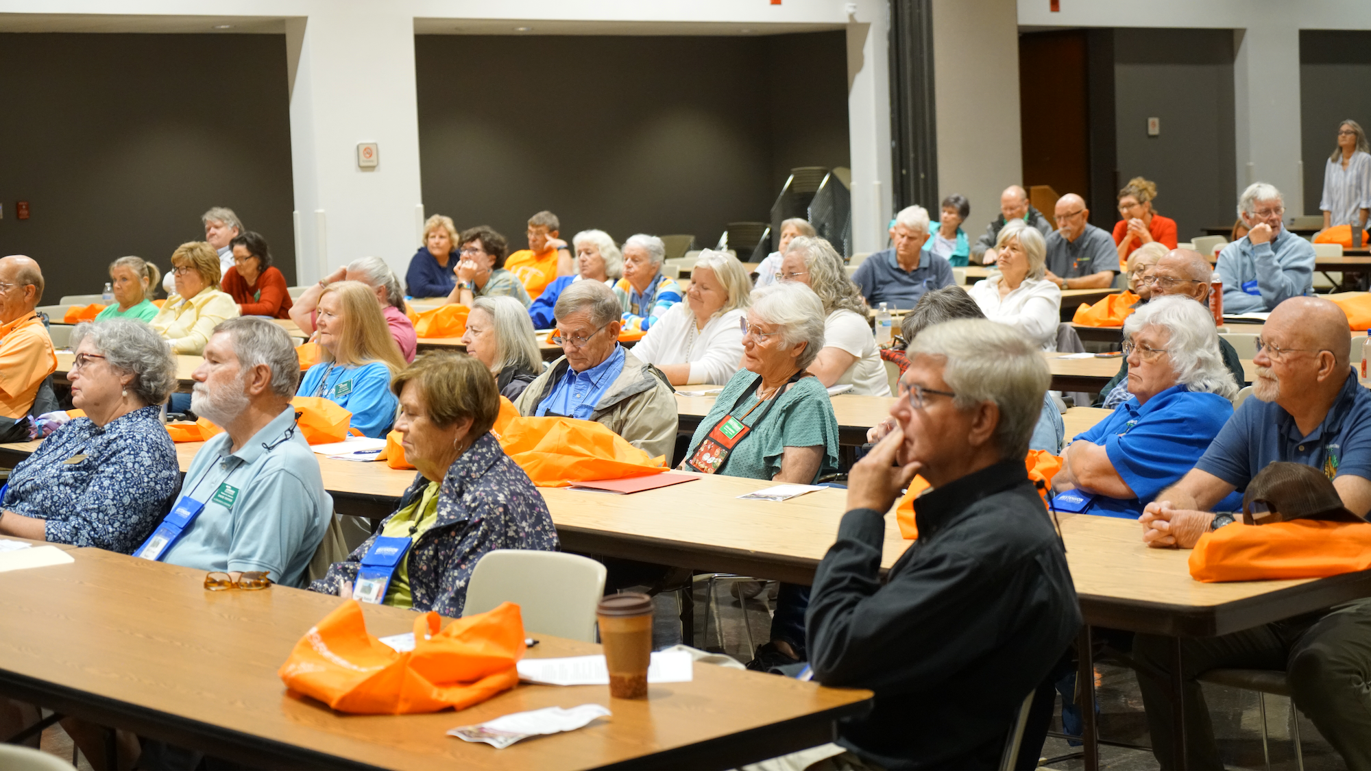 People in a crowded auditorium listen to a speaker at Fall in the Gardens