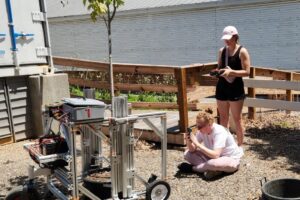 Darlene Player and Bailey Millsaps studying a Pot-in-Pot Extraction Robot prototype