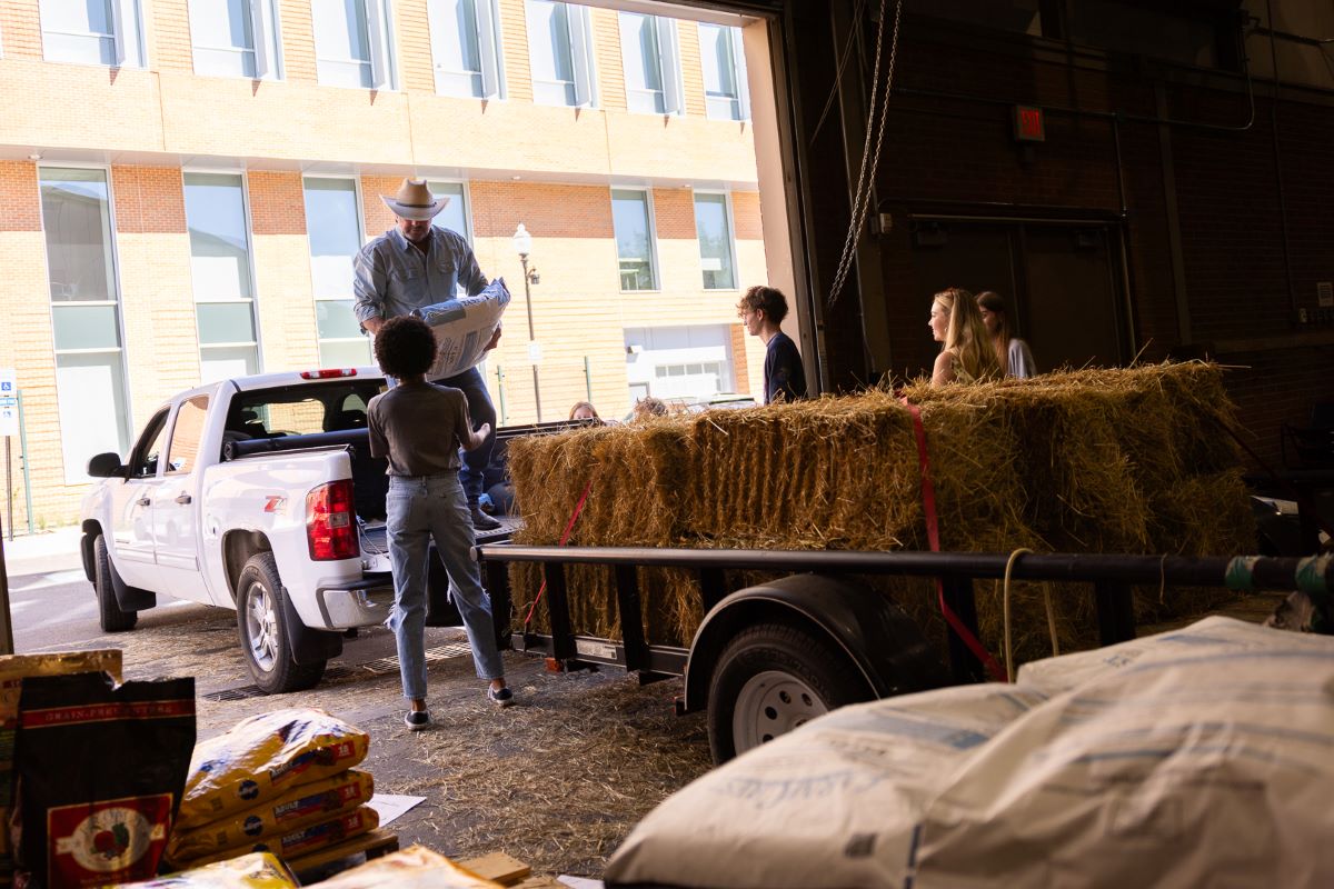 people loading a trailer with hay and animal feed