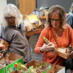 Two shoppers examine amaryllis bulbs in a lobby during the Amaryllis Sale