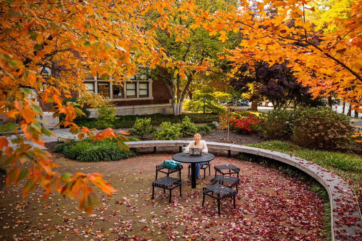 A student sitting outside at a table with a laptop