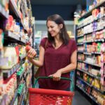 A woman shopping in a grocery store with a basket