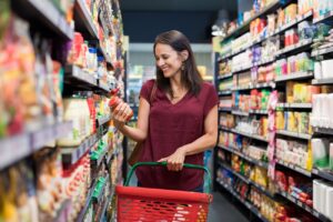 A woman shopping in a grocery store with a basket