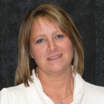 A headshot of a woman in a white t-shirt smiling at the camera