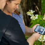 Becky Trout Fryxell and Angela Tucker holding a phone with the VECTOR Library on the screen