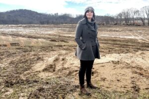 Emine Fidan standing in a field that was impacted by floods