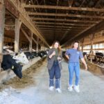 Ansley Roper and Jessica Halfen walking through a dairy barn