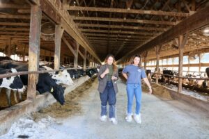 Ansley Roper and Jessica Halfen walking through a dairy barn