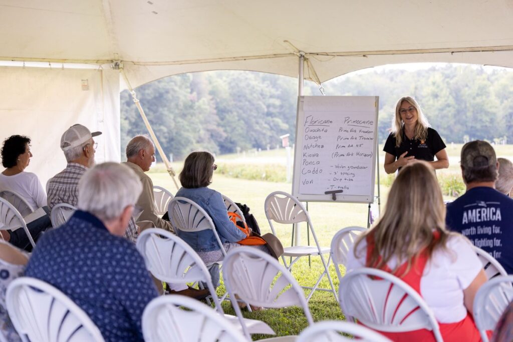 Natalie Bumgarner presenting to a crowd under a white tent
