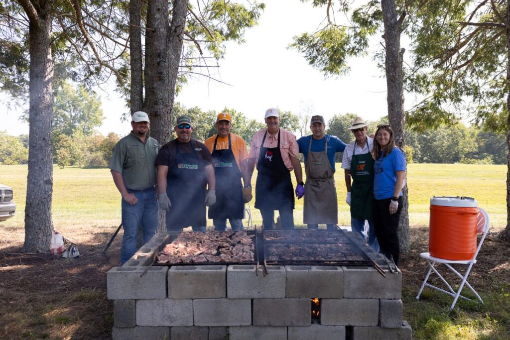 a group of people behind steaks on a grill