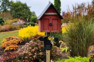 A box shaped like a barn on a post in a garden