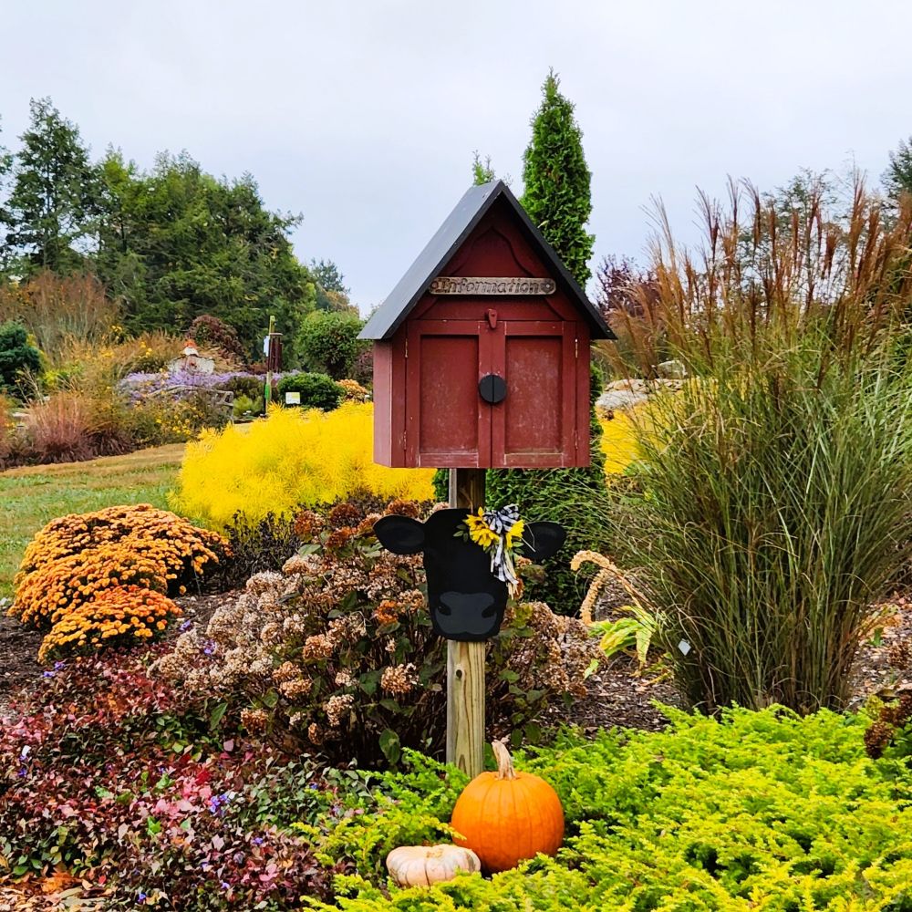 A box shaped like a barn on a post in a garden