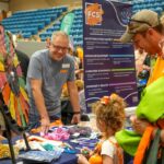 Chris Sneed talking with a family at the Family and Consumer Sciences Booth at Ag Day 2024