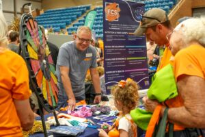 Chris Sneed talking with a family at the Family and Consumer Sciences Booth at Ag Day 2024