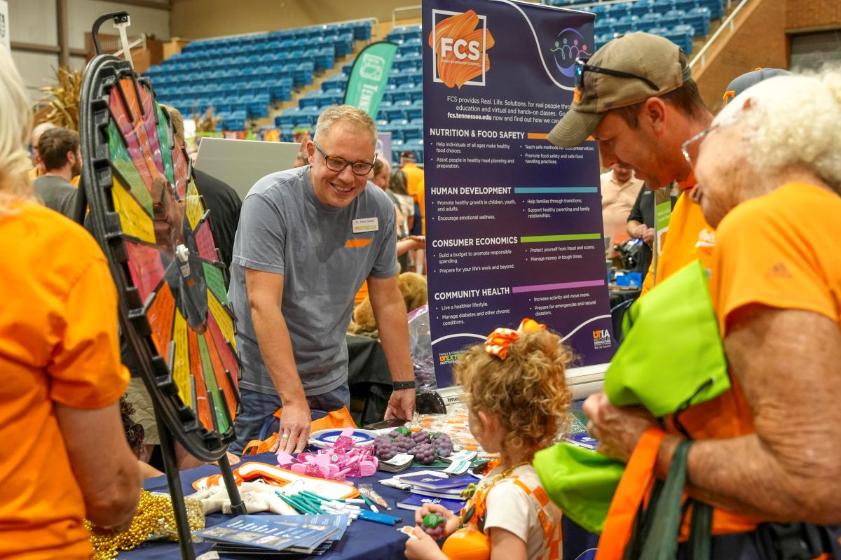 Chris Sneed talking with a family at the Family and Consumer Sciences Booth at Ag Day 2024