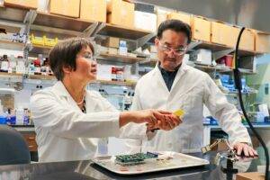 Jayne Wu, left, and Shigetoshi Eda work on a biosensor device that detects PTSD.