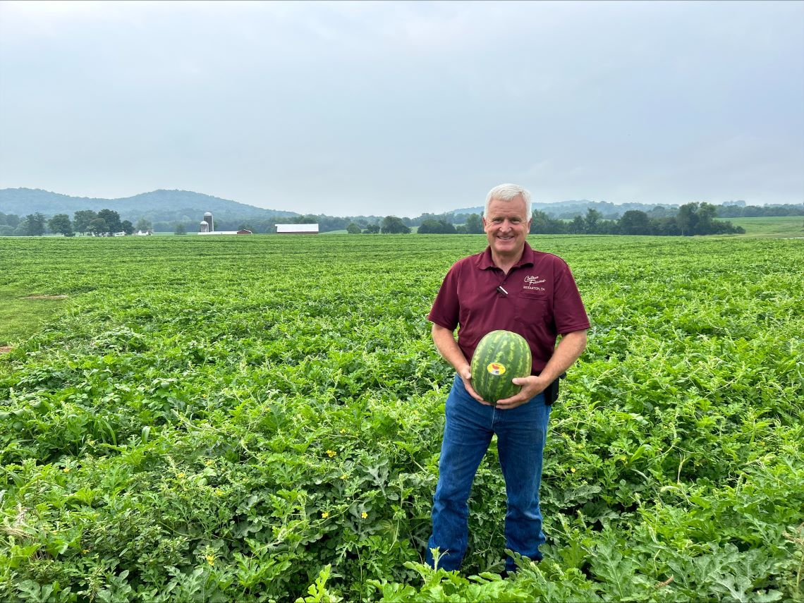 George McDonald holding a watermelon in a field