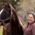 Martha Mallicote standing next to a brown horse