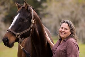 Martha Mallicote standing next to a brown horse