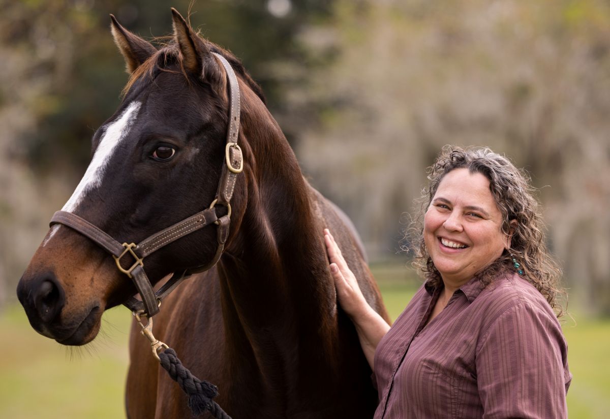 Martha Mallicote standing next to a brown horse