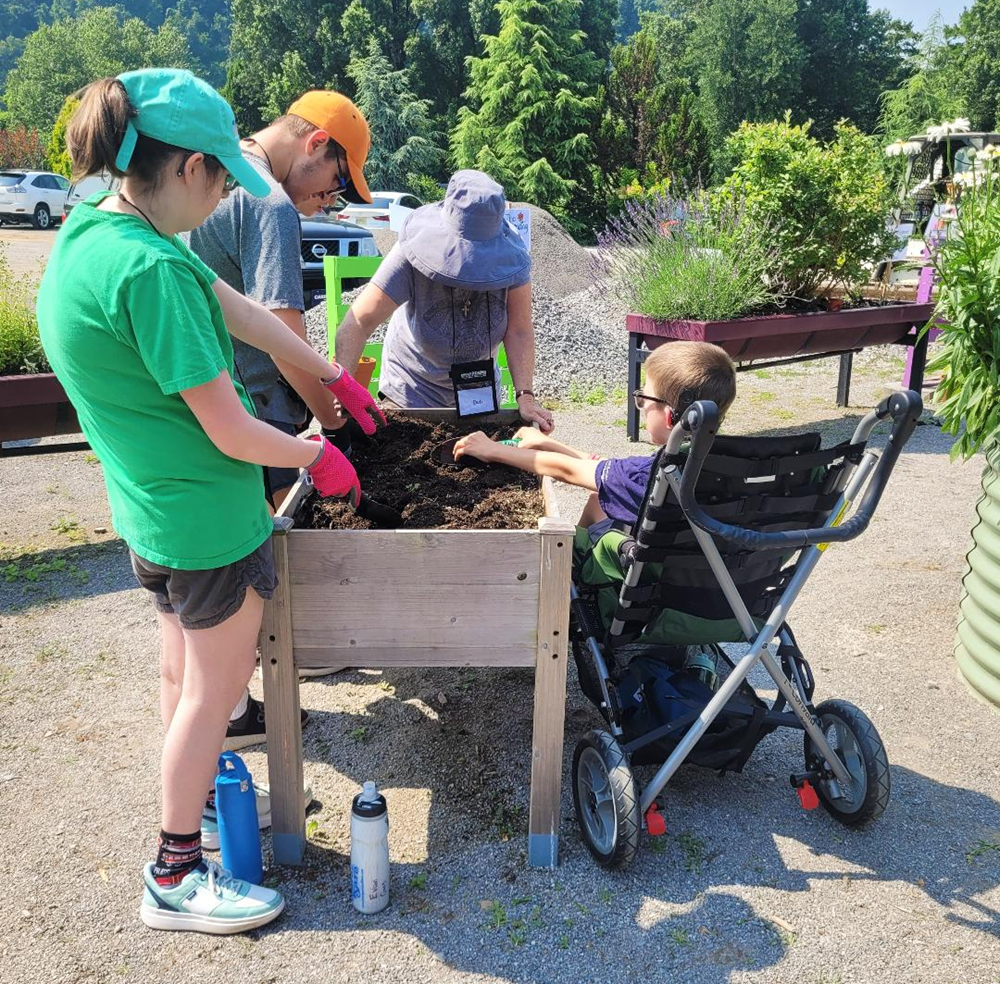 adults and a child utilize a handicap accessible raised bed at the UT Gardens, Knoxville’s Education Garden