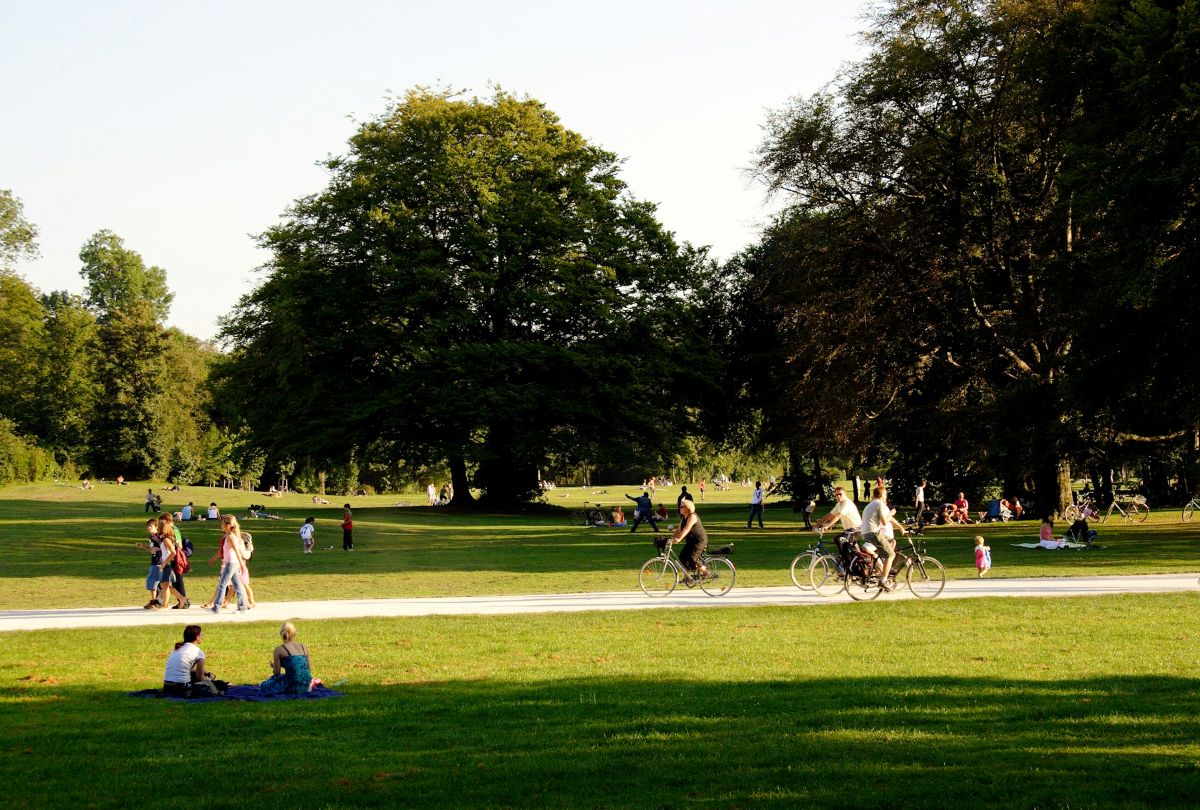 people walking, riding bikes, and sitting on grass at a park