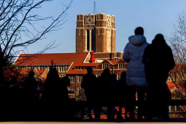 Students walk on UT campus with Ayres Hall in the background